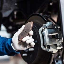 Mechanic showing worn out brake pad.